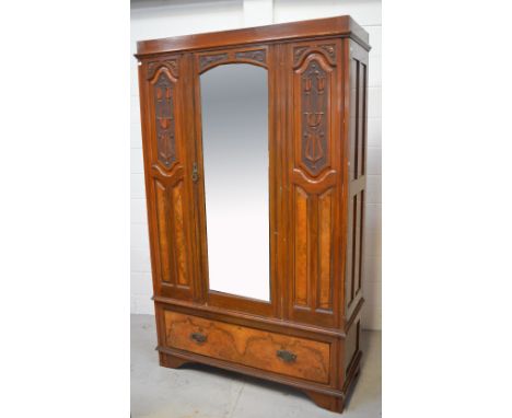 An Edwardian mahogany and walnut mirror door wardrobe with carved Art Nouveau panels to either side over one long drawer, on 
