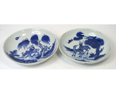 A pair of late 19th century Chinese blue and white bowls, one decorated with a stag and deer beside a bat in a tree set lands