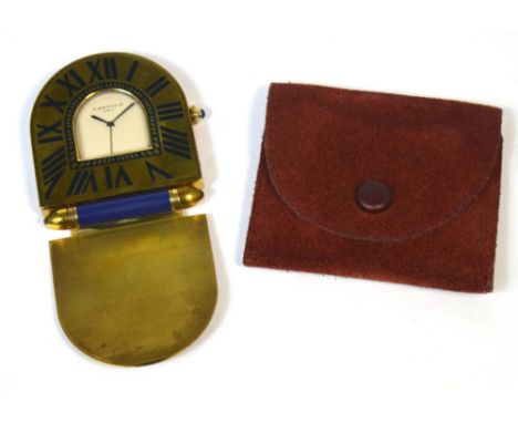 CARTIER; a brass quartz travelling clock with cabochon to the winding crown, Roman numerals to the shaped dial and the case i