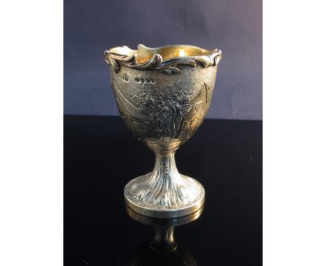 A silver egg cup with wavy edge and scenes of village, London 1859, 61g