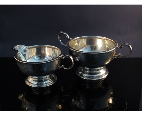 A silver twin handled sugar bowl with beaded edge on circular footed base (dented) and a matching milk jug, makers marks rubb