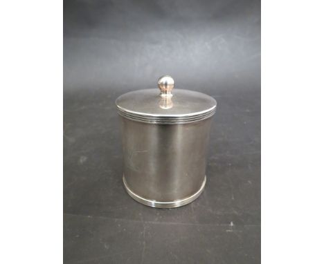 A white metal drum tea caddy with hinged lid and finial. Engraved with arm and sword from water, 7cm diameter