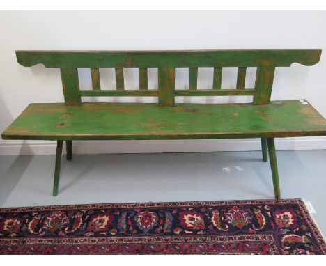 An antique pine bench with back, supported on stick legs - old green paint - Width 176cm