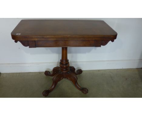 A 19th century walnut fold over card table on a carved quatrefoil base 