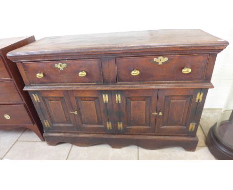 An 18th century oak dresser base with two drawers over two panelled cupboard doors raised on bracket feet with a good patina 