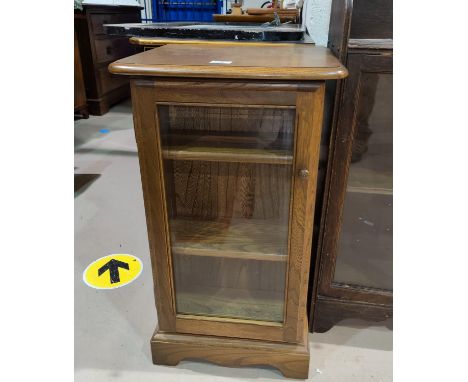 An Ercol small cabinet with glazed door and small shelves to side 