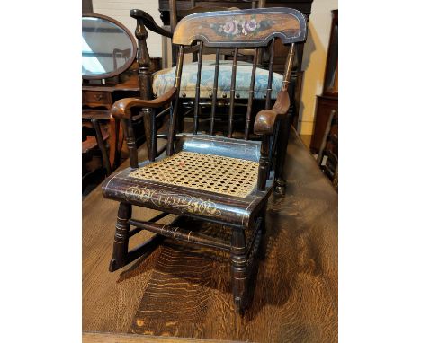 A 19t century child's rocking armchair with stick back and cane seat, painted decoration 