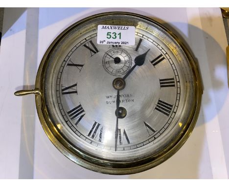 A ships clock in cylindrical brass case, with silvered dial, by Wm Jenkins, Dumbarton, diameter 18 cm Clock looks like it has