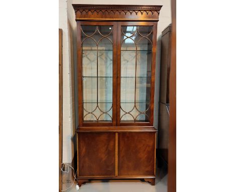 A Georgian style crossbanded mahogany full height bookcase with twin glazed doors over double cupboard, on bracket feet, heig
