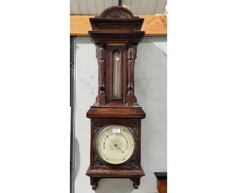 An early 20th century large barometer with thermometer, in wall hanging oak case with turned side pillars and carved spandrel