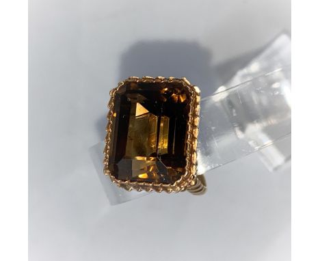 A 1970's yellow metal dress ring with ribbed decoration, set large cushion cut smoky quartz, 11 gm, unmarked, tests as circa 