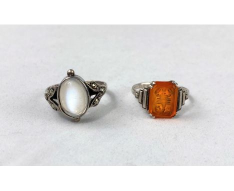 A white metal dress ring set oval moonstone, with marcasite shoulders, stamped 'silver'; a white metal dress ring set amber c