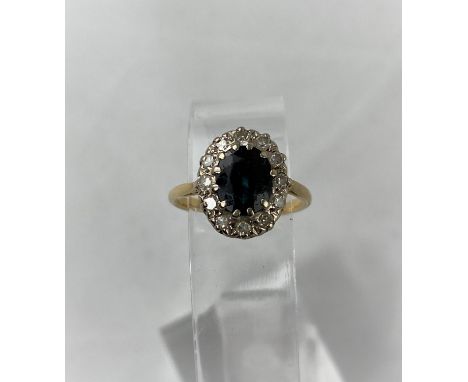 A lady's dress ring set central sapphire and 12 diamond surround, yellow metal shank stamped '18ct', 3.3gm, size J/K Sapphire