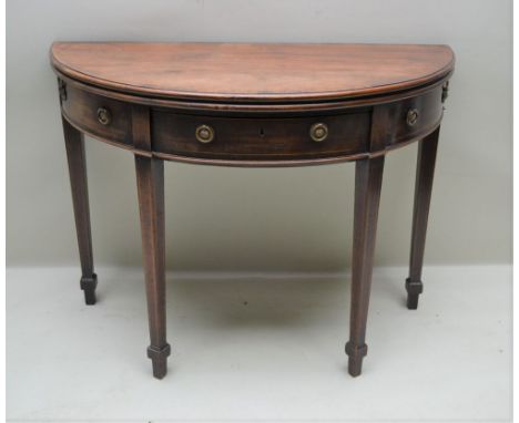 A GEORGE III MAHOGANY FOLD OVER DEMI-LUNE TEA TABLE, fitted central frieze drawer and two faux drawer fronts flanking, with b