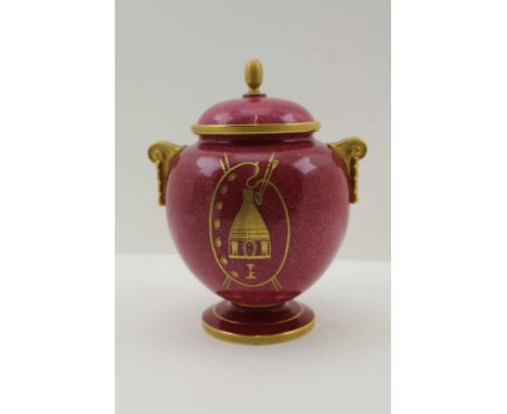 A ROYAL WORCESTER PORCELAIN LIDDED VASE, gilded crimson ground, decorated to one side with a palette and kiln, to the other a