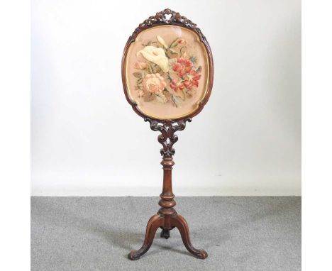 A Victorian carved walnut fire screen, with an oval tapestry and raised woolwork panel, 132cm high