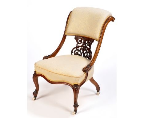 A Victorian walnut easy chair, the upholstered stuff-over back flanked by scrolling acanthus carved supports above a pierced 