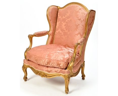 A 19th Century French giltwood wing back easy chair, serpentine cresting rail and moulded sides, acanthus carved sweeping arm