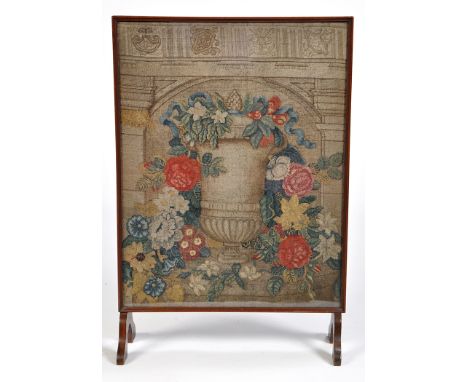 A 19th Century needlework firescreen, decorated with an urn of flowers centring architectural design, in an Edwardian mahogan