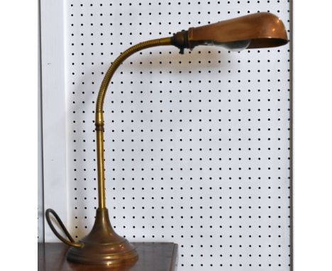 A vintage brass circular based adjustable desk lamp