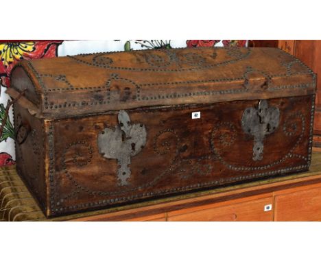 An antique dome studded leather trunk with large metal work escutcheons and having a floral fabric interior and iron work loo