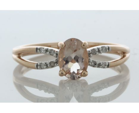 An oval 7mm x 5mm pink morganite sits between a double band of eight round brilliant cut diamonds set in the shoulders of thi