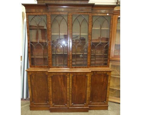 A small narrow Georgian mahogany breakfront bookcase, the moulded cornice above four Gothic astragal-glazed doors and four pa