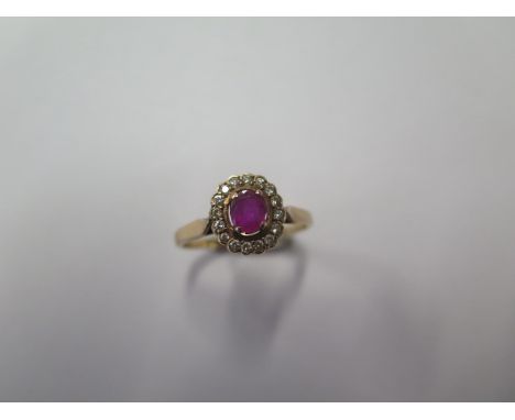 An all yellow gold ruby and diamond cluster ring with a 4.5mm x 3.7mm oval Burma ruby surrounded by 16 0.01ct pave set brilli
