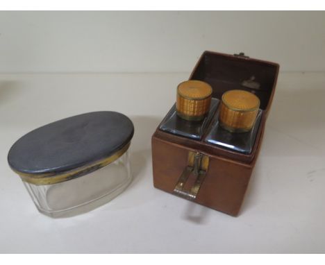 A silver top glass tidy, top approx 1.9 troy oz and a leather cased two bottle cologne scent set with enamel tops- missing a 