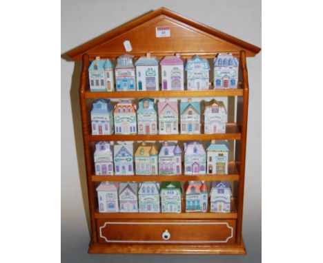 A set of 24 Brooks &amp; Bentley ceramic herb jars and covers, each in the form of a house, in four tier wall rack with drawe