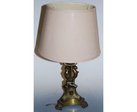 A brass table lamp and shade, having acanthus leaf capital with figural animal supports, to a triform base