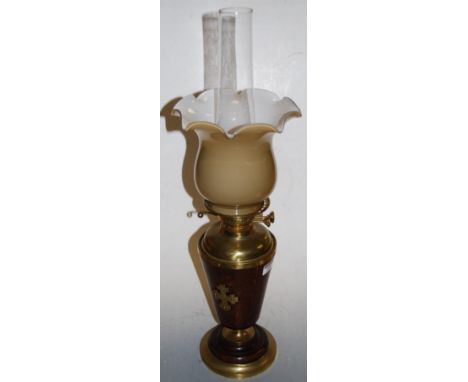 A 1920s oak and brass pedestal oil lamp, having associated shade with brass reservoir, and conical oak body to a circular foo