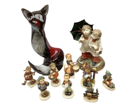 West German style figure modeled as a seated fox, together with seven Hummel figures, to include girl with guitar, boy seated