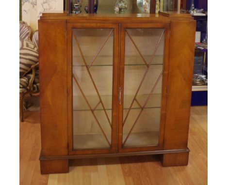 Art deco maple display cabinet with geometric glass panel doors opening to inside glass shelves, 122cm wide, 32.5cm deep, 126