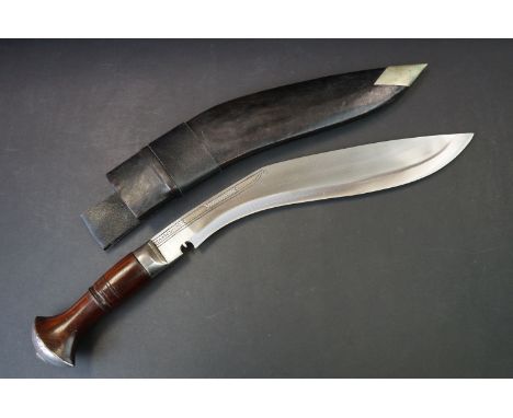 A Nepalese Kukuri knife with fullered steel blade, wooden grip and brass fittings, complete with scabbard. 