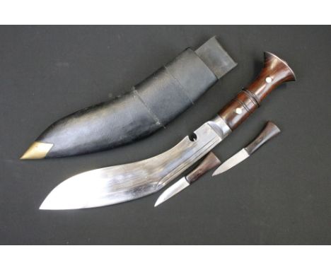 A Nepalese Kukuri knife with fullered steel blade, wooden grip and brass fittings, complete with scabbard and tools. 