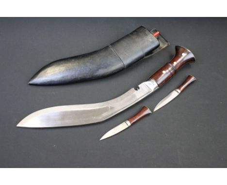 A Nepalese Kukuri knife with fullered steel blade, wooden grip and steel fittings, complete with scabbard and tools. 