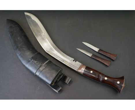 A large Kukuri knife with steel bade, wooden handle with mother of pearl inlay and steel fittings, complete with leather scab