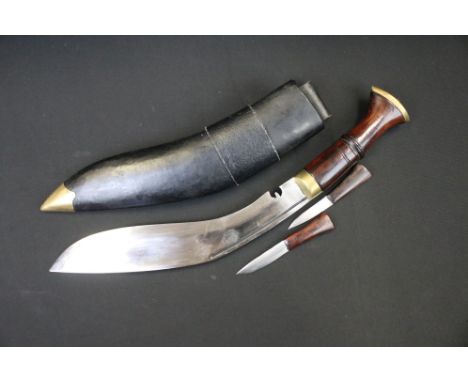 A Nepalese Kukuri knife with fullered steel blade, wooden grip and brass fittings, complete with scabbard and tools. 