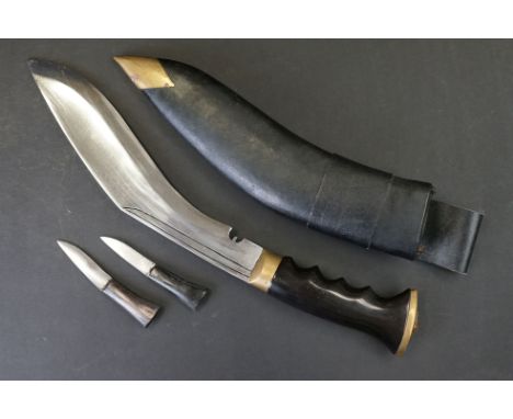 A Nepalese Kukuri knife, moulded grip and brass fittings, complete with scabbard and tools. 