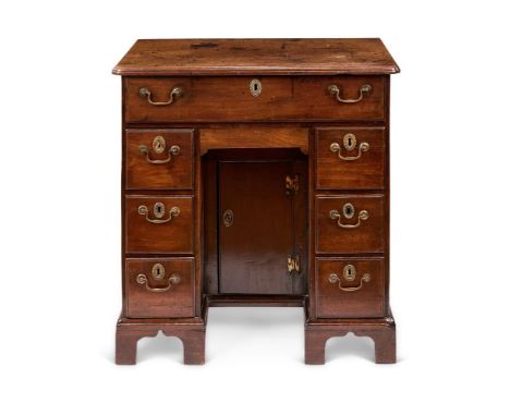 A GEORGE II MAHOGANY KNEEHOLE DESK OR DRESSING-TABLE  CIRCA 1750    The rectangular top and re-entrant corners above a long f