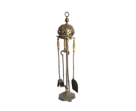 A large and unusual brass fireside companion stand, the pierced helmet shaped top surmounted by a ring handle, 105cm high; an
