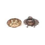 A silver shell shaped dish, having foliate engraved decoration, raised on three scrolled feet,
