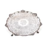 An Edwardian silver salver, having pie crust and shell decorated border, foliate scroll field and