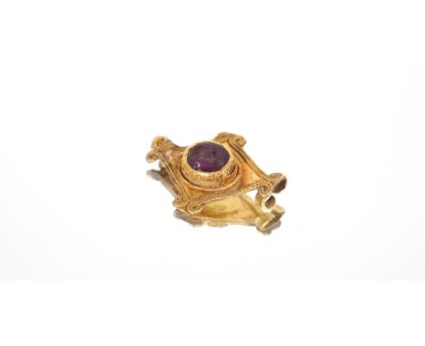 An antique yellow metal diamond shaped pendant,&nbsp;&nbsp;inset with a cornelian amethyst coloured stone within a filigree w