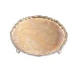 A silver salver, with gadrooned pie crust border raised on four stylised feet, Sheffield 1929,