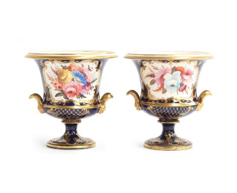 A pair of 19th century twin handled porcelain urns, each with hand painted floral panel on a cobalt blue ground, heightened i
