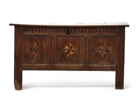 A 17th century three panel narrow oak coffer, the front with lozenge inlay, the end boards notched at the lower edges to form