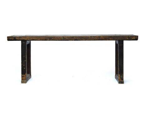 A substantial Asian hardwood console table, two plank top on end supports, clad in a fibrous material, 237.5cm long, 53cm dee