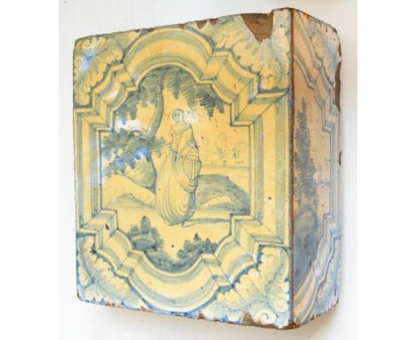A DUTCH DELFT CORNER TILE, PAINTED WITH A WOMAN STANDING BY A TREE IN SHAPED BORDER, THE RETURN WITH A HALF LANDSCAPE, 22 X 2